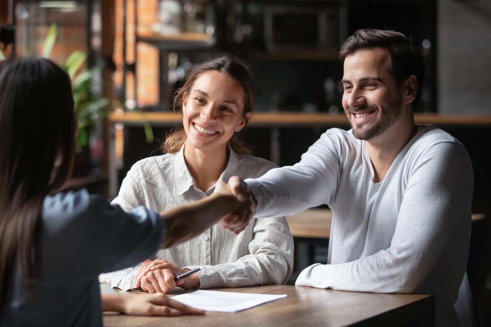 Couple shaking hands with loan officer over table