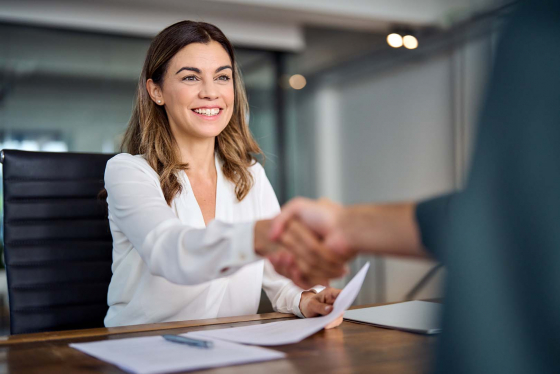 Woman shaking hands over desk with client