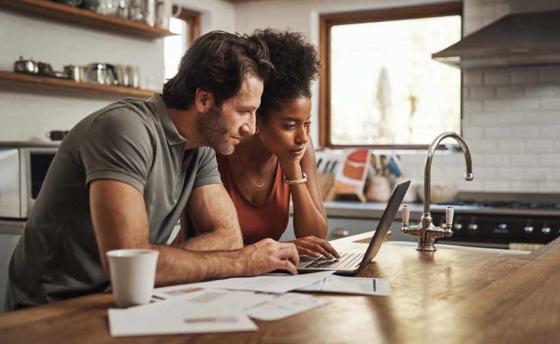 Couple looking at laptop with coffee and papers around