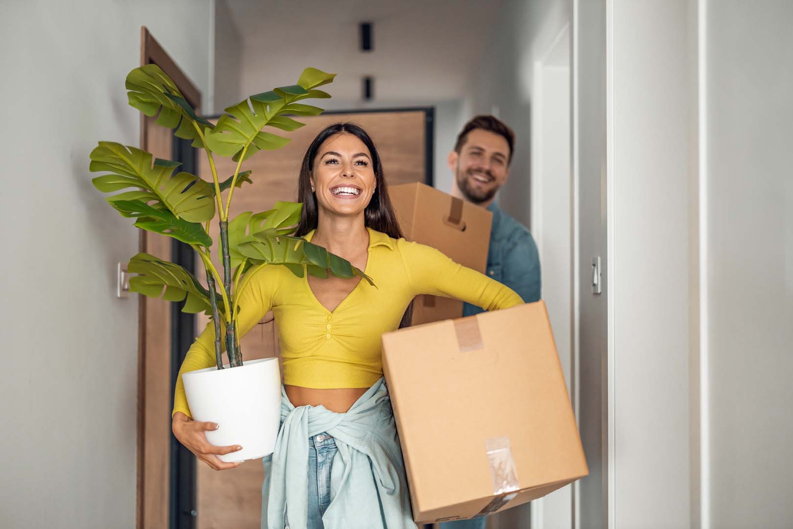 Man and Woman walking into home with boxes